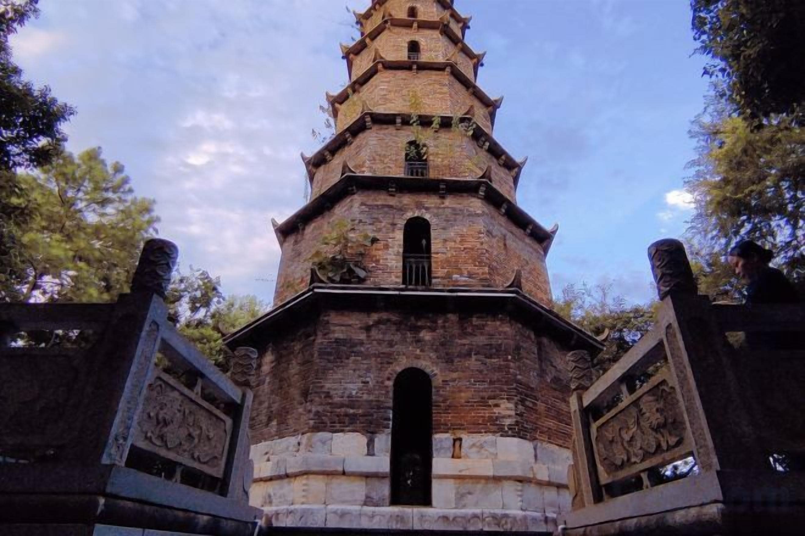 A brick pagoda with a central door and a multi-tiered roof.