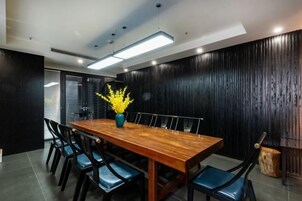 A conference room with a wooden table, black chairs, and a vase with yellow flowers.
