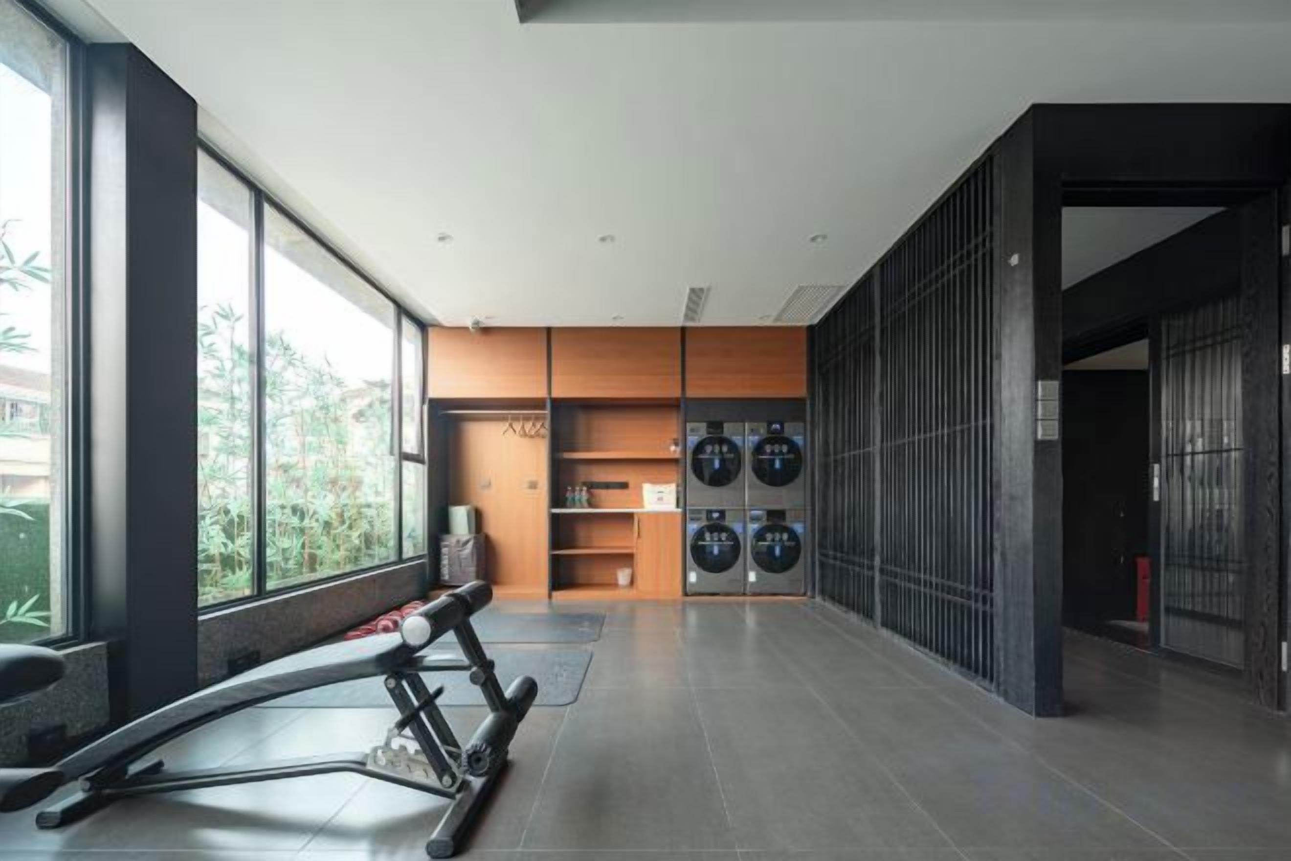 A modern gym with exercise equipment, a laundry area, and large windows.