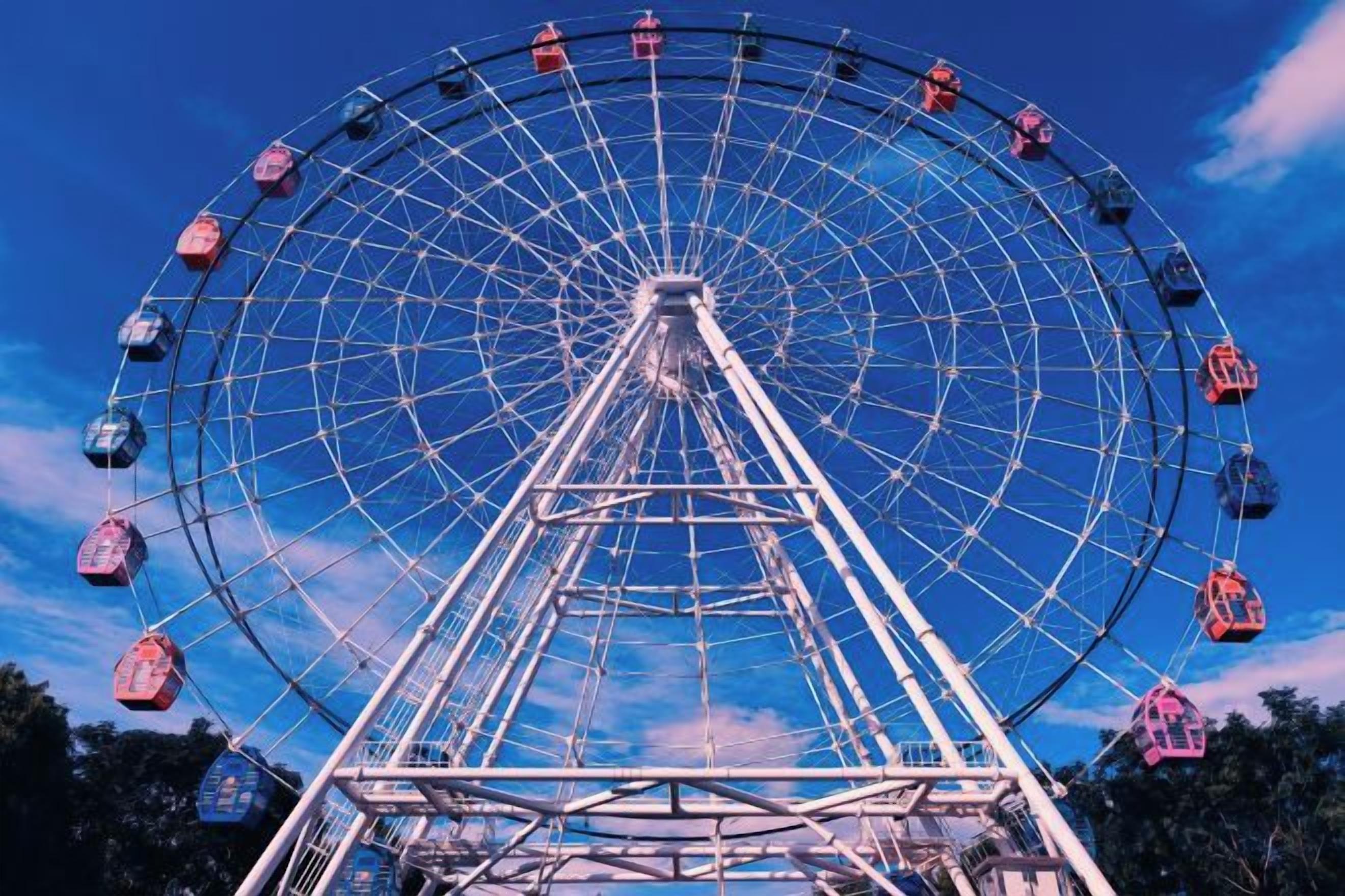 A large Ferris wheel with cabins, set against a clear sky.