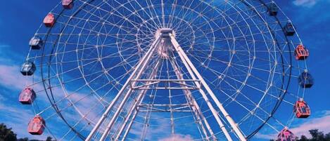 A large Ferris wheel with cabins, set against a clear sky.