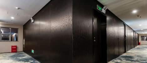 A hallway with a black wall, a door, and a carpeted floor.