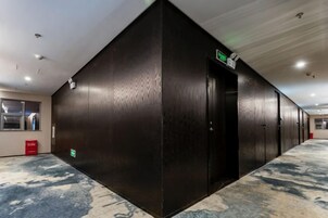 Um corredor com parede preta, uma porta e piso coberto de carpete.