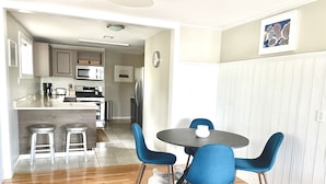 A modern kitchen with a central island, bar stools, and a dining area with a round table and blue chairs. - Updated, 2 Bedroom Cottage, close to Boulder (Lafayette)