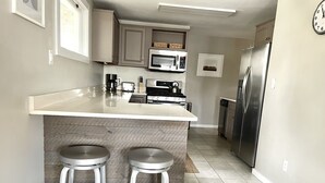 A modern kitchen with a central island, stainless steel appliances, and two bar stools. - Updated, 2 Bedroom Cottage, close to Boulder (Lafayette)