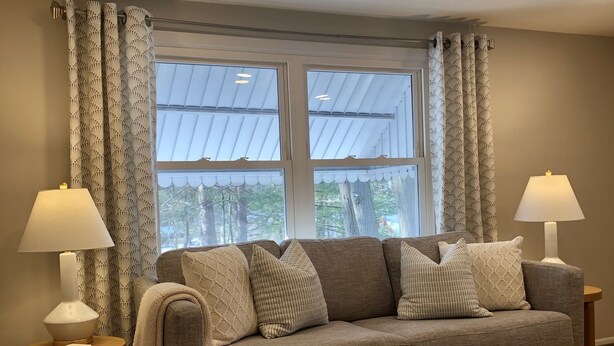 A living room with a sofa, two lamps, a coffee table, and a window with curtains.