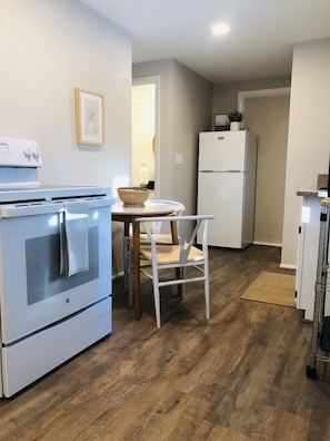 Compact kitchen with a stainless steel oven, refrigerator, and dining table.