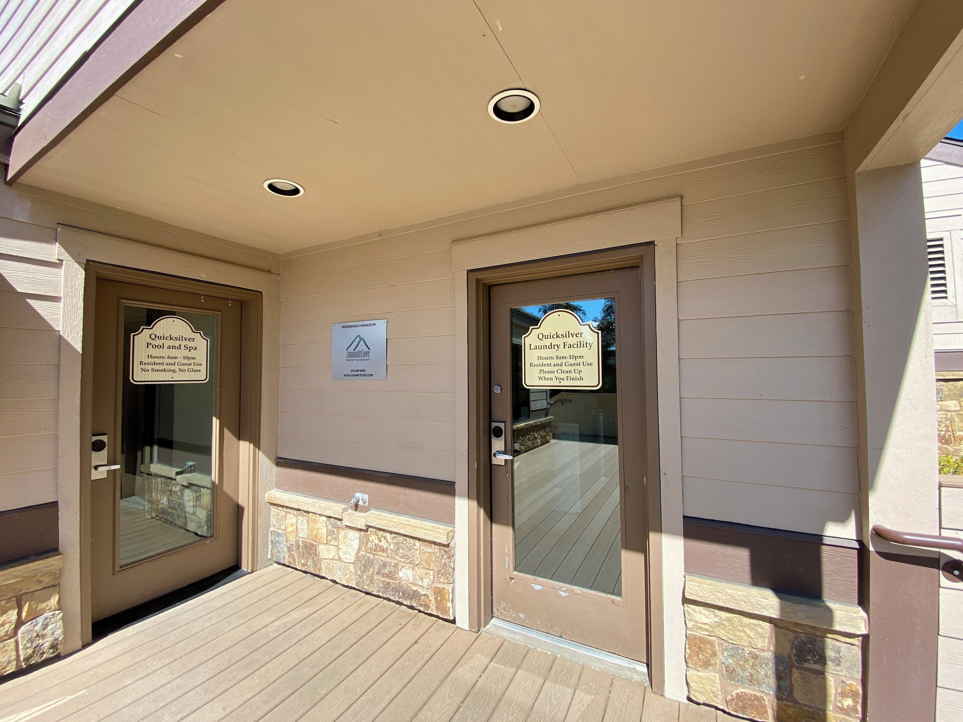 A building entrance with two doors, each with a sign indicating services: a pool and spa, and a laundry facility.