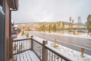 A snowy landscape with a road, trees, and a building with a balcony. - River Run Townhomes 66 (Keystone)