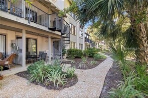 Un immeuble résidentiel à plusieurs étages doté de balcons, d’espaces de détente en plein air et de jardins aménagés.