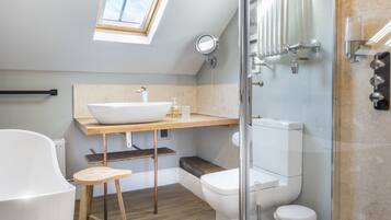 Un baño moderno con tragaluz, una bañera independiente, una ducha con cerramiento de vidrio y un inodoro.