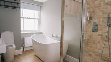 A modern bathroom with a freestanding bathtub, a glass shower enclosure, and a window providing natural light.
