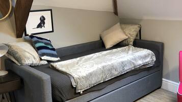 A cozy room with a grey sofa, a framed picture on the wall, and a wooden beam structure above.