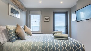 A bedroom with a bed, pillows, a TV, and a window with a view. - The Royal George (Bideford)