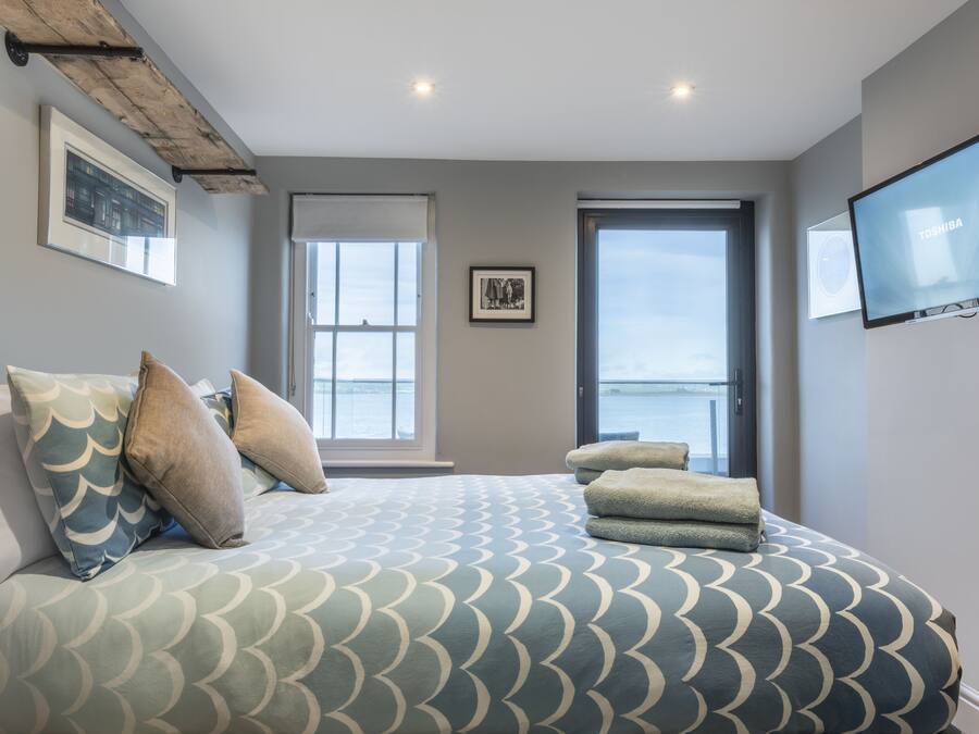 Ein Schlafzimmer mit Bett, Kissen, Fernseher und einem Fenster mit Blick.