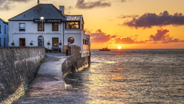 A waterfront building named "Royal George" with a stone wall and a dock extending into the water. - The Royal George (Bideford)