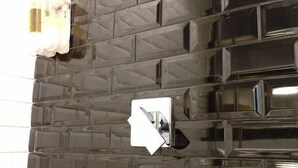 A wall with a textured, dark-colored surface and a reflective, metallic object that appears to be a light switch or control panel. - Fanpu Art Hotel (Jiaxing)