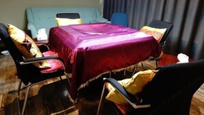 A room with a bed, a table with a purple tablecloth, and four chairs with yellow cushions. - Fanpu Art Hotel (Jiaxing)