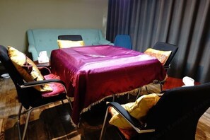 A room with a bed, a table with a purple tablecloth, and four chairs with yellow cushions. - Fanpu Art Hotel (Jiaxing)