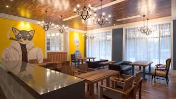 A restaurant interior with wooden flooring, a central bar area, and a mural of a cat on the wall.