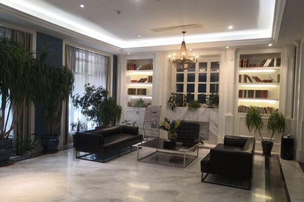 A spacious living area with a large window, a fireplace, and a bookshelf filled with books. - Fanpu Art Hotel (Jiaxing)