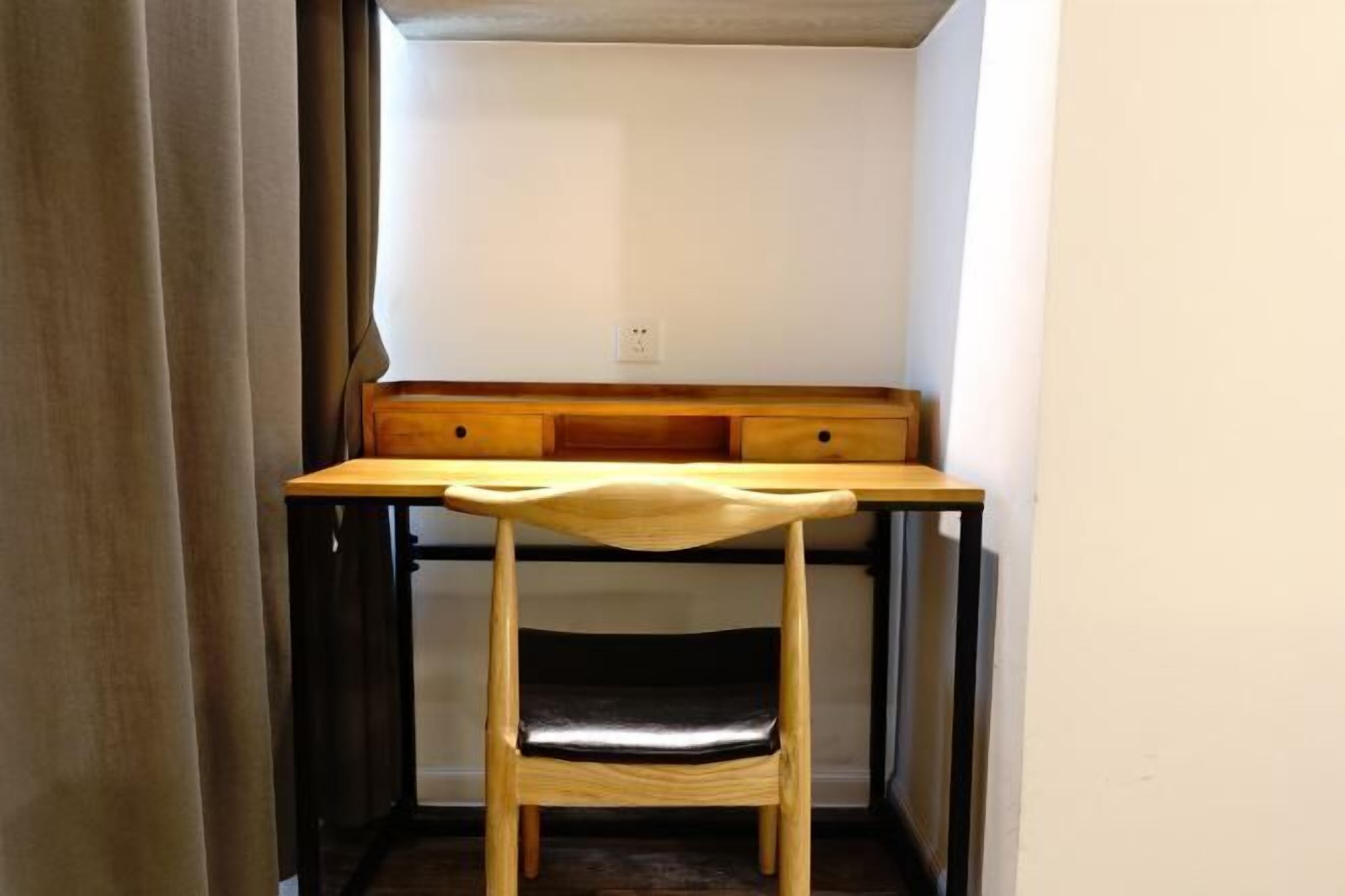 A corner room with a wooden desk, a chair, and a built-in bench.
