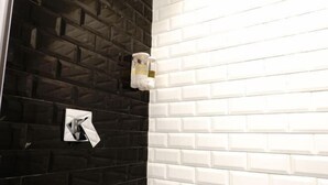 A bathroom with black and white tiled walls, a towel dispenser, and a hand dryer. - Fanpu Art Hotel (Jiaxing)