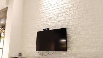 Un téléviseur à écran plat fixé sur un mur en briques blanches.