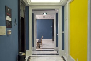 A hotel corridor with a blue wall, a yellow door, and a chair in the distance. - Fanpu Art Hotel (Jiaxing)