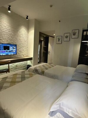 Habitació d'hotel amb paret de maó, televisió de pantalla plana, llit amb roba de llit blanca i porta que dona a un bany.