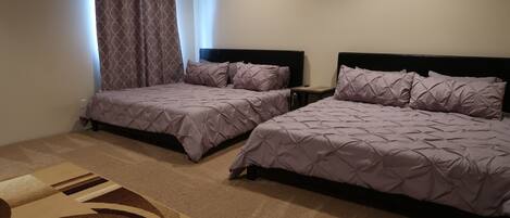 A hotel room with two beds, a small bedside table, a nightstand, and a patterned rug.