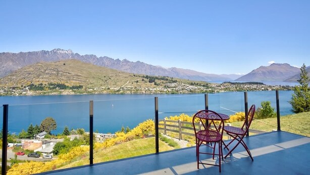 A terrace with a table and chairs overlooking a lake and mountains. - Ultimate Heights Queenstown Jaw dropping views (Queenstown)
