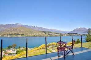 A terrace with a table and chairs overlooking a lake and mountains.