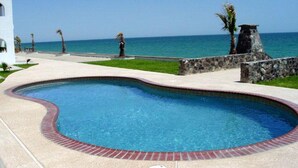 A swimming pool with a curved edge, a stone wall, and a view of the ocean. - Paradise Villa 20 by Kivoya (Puerto Peñasco)