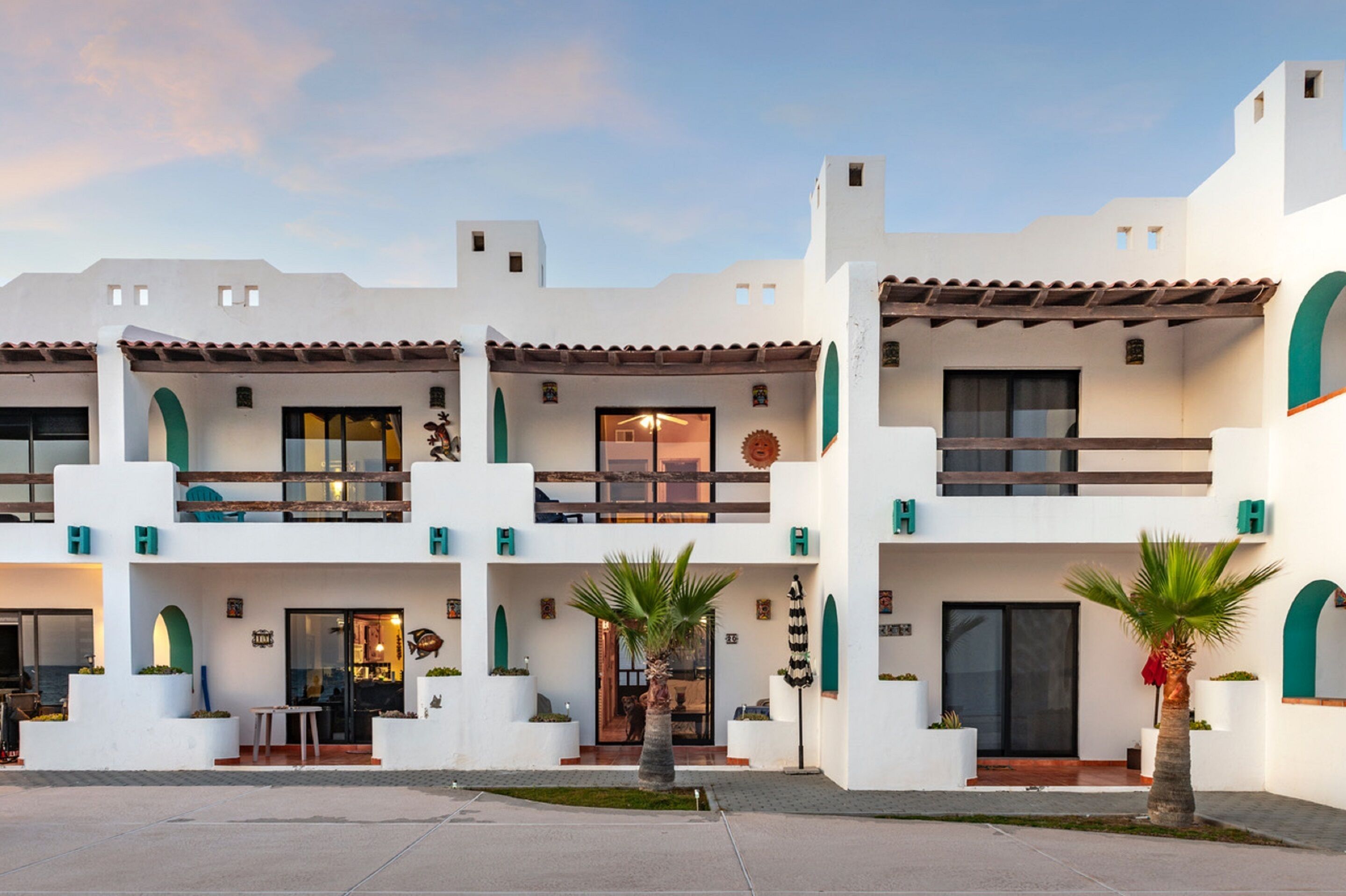 A two-story building with a white facade, multiple balconies, and a covered outdoor seating area.