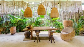 A tropical-themed room with a wooden table, wicker chairs, and hanging lamps. - Luxury & Nature Meet Plus a Private Pool & Roof Pool (Tulum)