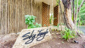 A wooden sign with "Sky Jungle" written on it, set against a backdrop of a bamboo fence and a tree. - Luxury & Nature Meet Plus a Private Pool & Roof Pool (Tulum)