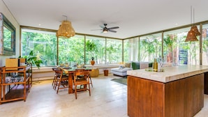 A spacious kitchen with a large island, wooden furniture, and large windows offering a view of lush greenery. - Luxury & Nature Meet Plus a Private Pool & Roof Pool (Tulum)