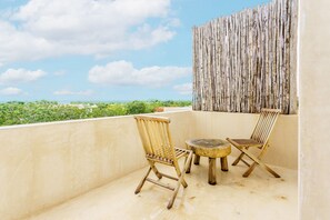 A balcony with two wooden chairs and a small round table, overlooking a coastal landscape. - Luxury & Nature Meet Plus a Private Pool & Roof Pool (Tulum)