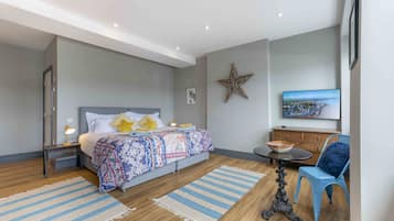 A modern bedroom with a large bed, a small table, a chair, a star decoration, and a TV on the wall.