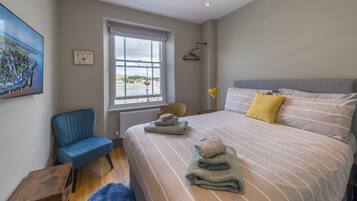A bedroom with a large bed, a chair, a window, and a painting on the wall.