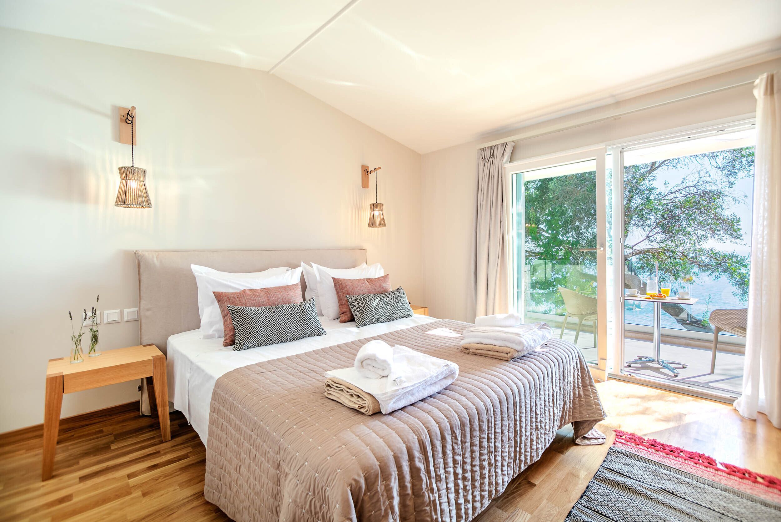 Ein modernes Schlafzimmer mit einem großen Bett, Nachttischen und Blick ins Freie.