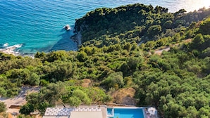 A villa with a swimming pool, surrounded by dense greenery and overlooking a coastal area with clear blue waters. - Ocean View - Luxury Villa Ethra (Corfu)