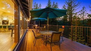 A wooden deck with outdoor seating, including tables and chairs, and large umbrellas providing shade. - Serene Tahoe Escape | HotTub | Arcade | EV Charger (South Lake Tahoe)