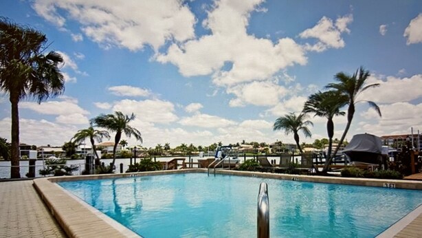 A rectangular swimming pool with a clear blue water surface, surrounded by a tiled deck. - Vanderbilt Beach area with Bay views from Lanai. (Naples)