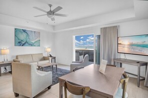 A modern hotel room with a dining area, a sofa, a TV, and a view of the beach. - Beach Front Condo at the Avalon Club (Clearwater)