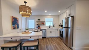 Una cocina moderna con una isla grande, electrodomésticos de acero inoxidable y una lámpara colgante.