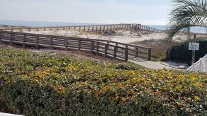 Strandudsigt med en træpromenade og et hvidt gelænder i forgrunden.