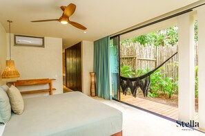 A bedroom with a bed, a ceiling fan, a window with curtains, and a view of a hammock and greenery outside. - Gorgeous Flowy Space with Wrap-around Private Pool (Tulum)