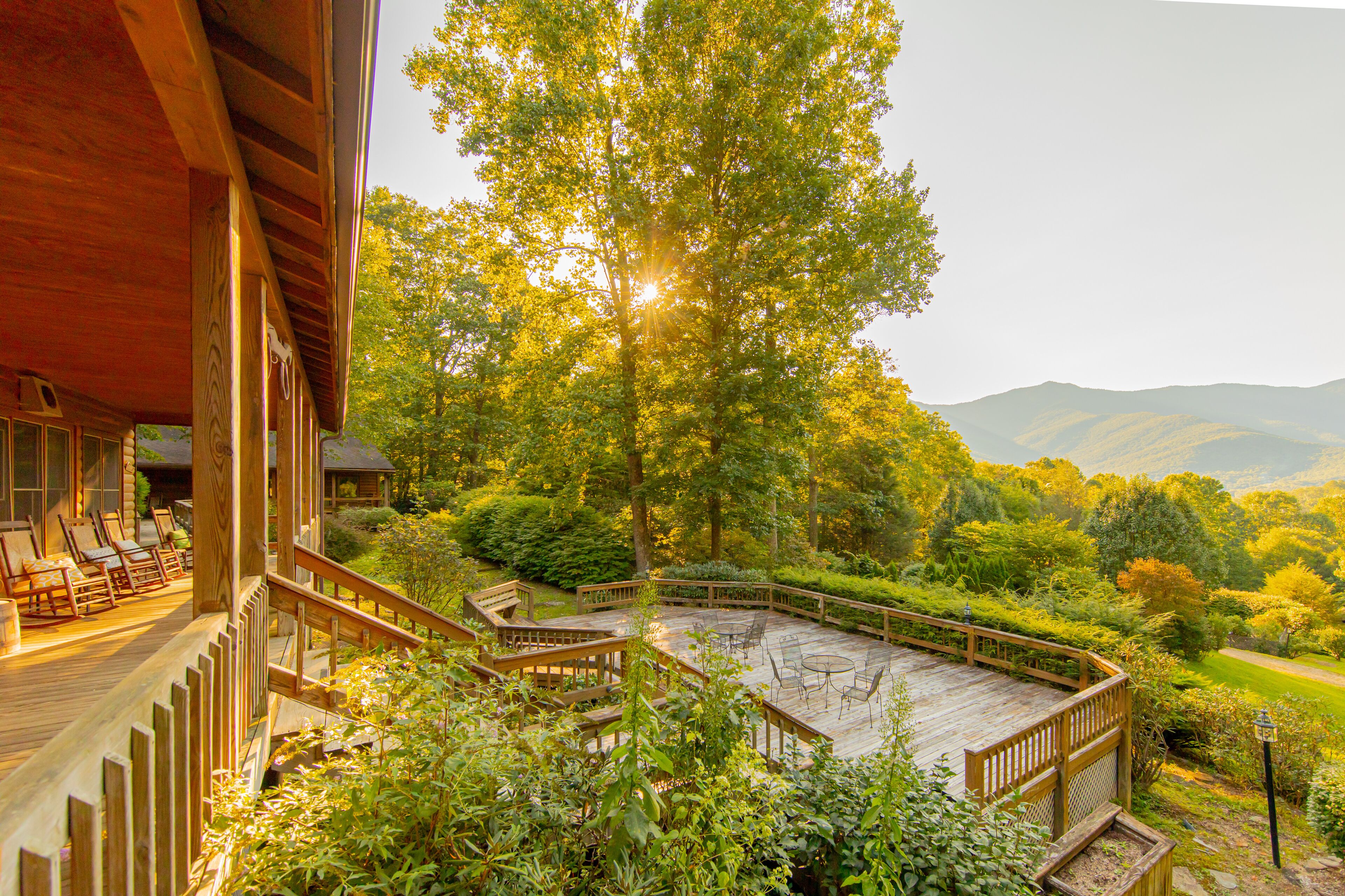 Un terrazza in legno con mobili da esterno, immersa nel verde e con vista su dolci colline.